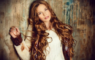 Fashion shot of a pretty teenager girl with beautiful long curly hair wearing fur coat. Beauty, fashion.