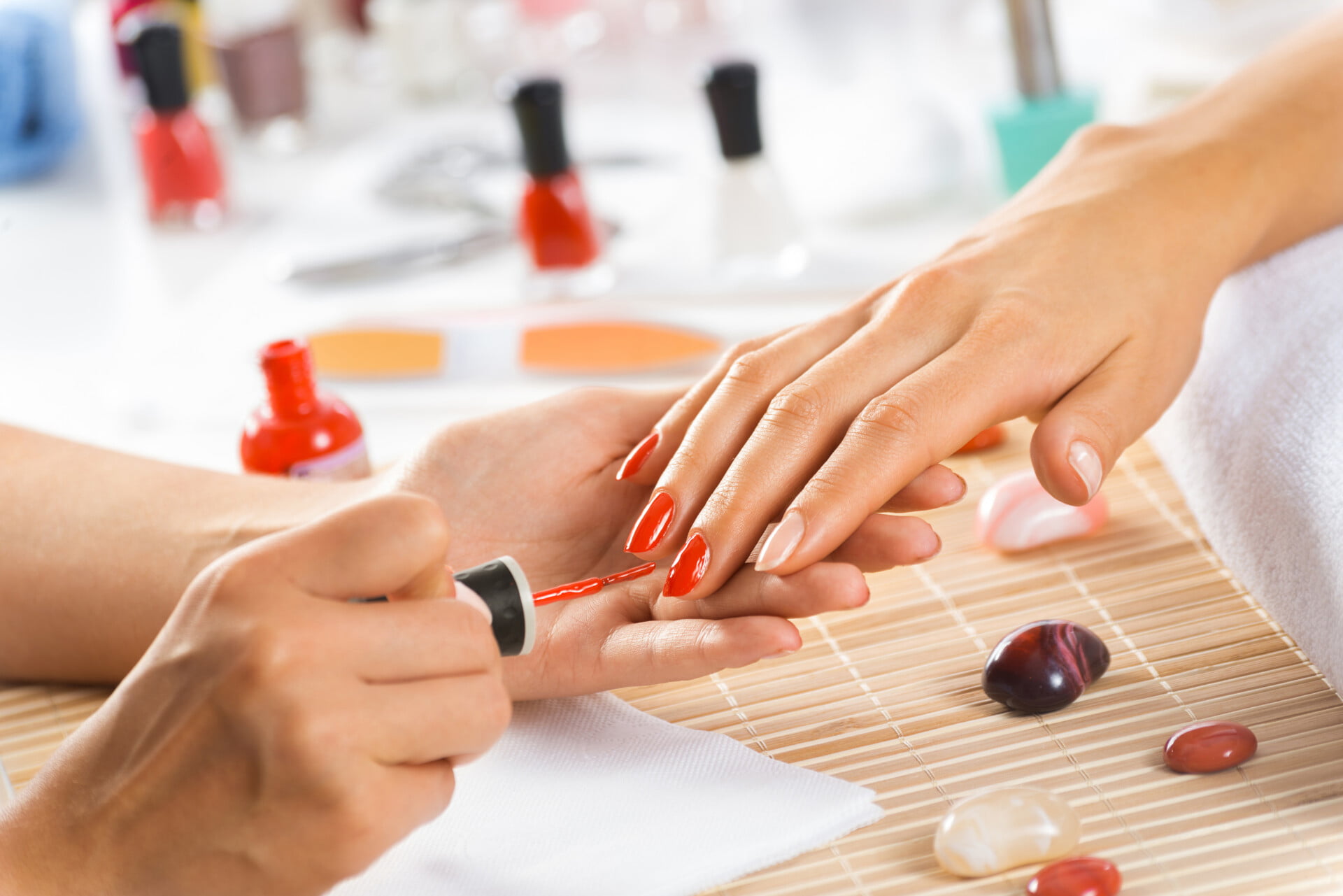 Woman in salon receiving manicure by nail beautician