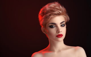 Perfect look. Attractive young female fashion model posing in red artistic lighting at studio on black background black smoky eyes red lips cosmetics beauty professional makeup concept copyspace